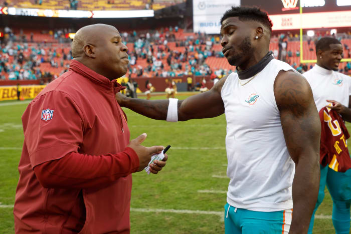 Miami Dolphins wide receiver Tyreek Hill (R) hugs Washington Commanders assistant head coach/offensive coordinator Eric Bieniemy (L) at FedExField.